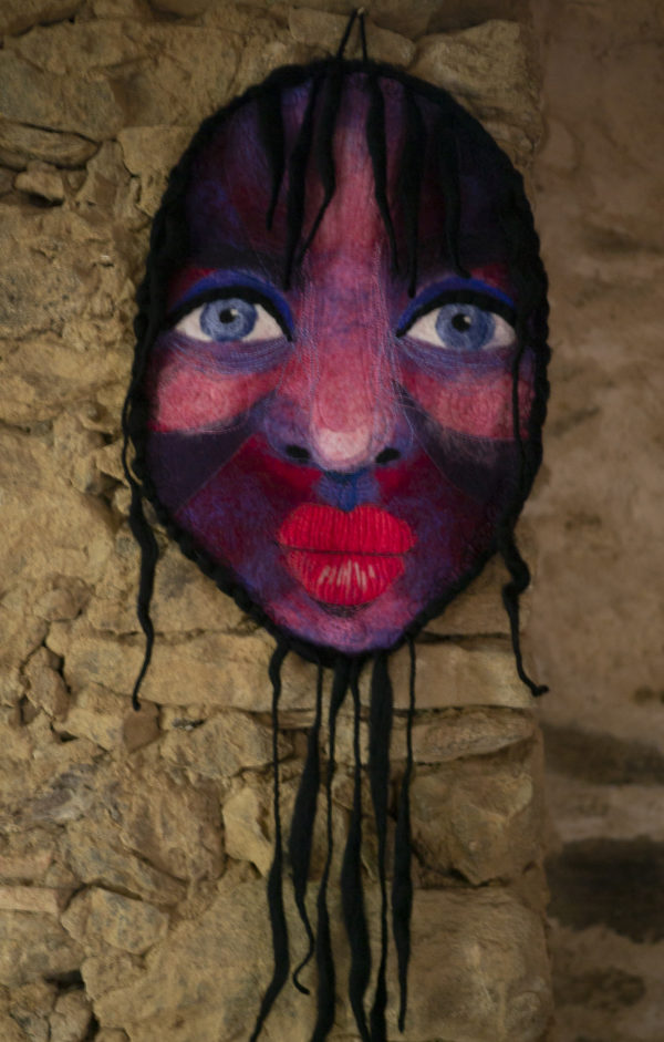 décoration murale visage en laine feutrée sur un mur en pierre